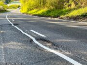 O buraco é muito problema! O empreiteiro do conselho desenha linhas brancas em cima do grande buraco antes de ser preenchido