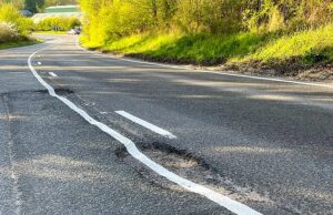 O buraco é muito problema! O empreiteiro do conselho desenha linhas brancas em cima do grande buraco antes de ser preenchido