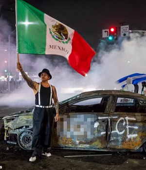 103550927-15253391-A_protester_waves_the_Mexican_flag_beside_the_wreckage_of_a_burn-a-21_17621921534.avif
