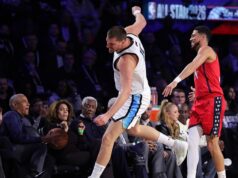 Obama pega uma bola perdida enquanto está sentado na quadra com Michelle no NBA All-Star Game