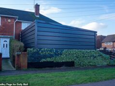 Proprietário descarado desafia ordem do conselho para demolir a imponente megagaragem ilegal – apesar dos vizinhos insistirem que a ‘fortaleza’ arruinou suas vidas