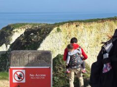 Pai ignorante mochilando criança arriscando suas vidas ignorando sinais de alerta para ter uma vista do topo do penhasco
