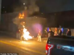 Um manifestante queimando uma bandeira acidentalmente se incendeia fora de uma instalação do ICE