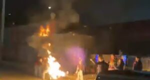 Um manifestante queimando uma bandeira acidentalmente se incendeia fora de uma instalação do ICE