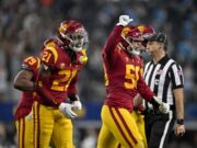 Alguns jogadores de futebol americano da USC exibem listras brancas em seus capacetes