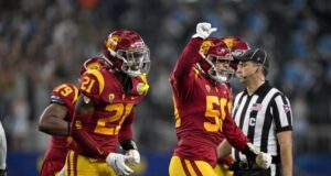 Alguns jogadores de futebol americano da USC exibem listras brancas em seus capacetes