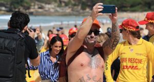 Somente na Austrália! Contrabandistas locais vestidos de Bondi abraçam o Príncipe Harry na icônica praia de Sydney