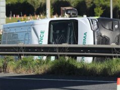 Uma mulher de 50 anos foi presa depois que uma ambulância capotou de lado em uma colisão com um carro e um caminhão – deixando cinco pessoas no hospital