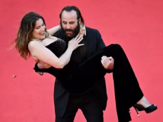 O ator francês Vincent McCain carrega a modelo Laetitia Casta pelo tapete vermelho enquanto a dupla faz uma exibição animada na estreia de Karma no Festival de Cinema de Cannes.