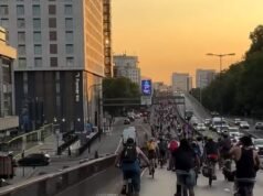 Ciclistas imprudentes puxam rodas de bicicletas elétricas ilegais e sobem em um pórtico após invadirem uma faixa de rodagem dupla para protesto anti-carros durante obras rodoviárias