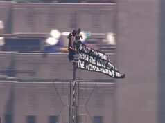 Cenas selvagens da dupla mascarada levando o Empire State Building ao topo e hasteando bandeiras de amor e paz