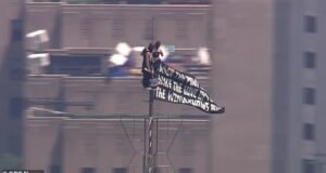Cenas selvagens da dupla mascarada levando o Empire State Building ao topo e hasteando bandeiras de amor e paz