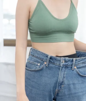 woman-weight-loss-flat-belly-oversized-jeans.webp