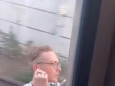Um homem bobo com uma camisa havaiana é visto aproveitando a brisa enquanto viaja em alta velocidade fora de um trem da Filadélfia