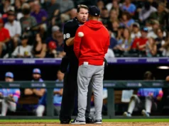 Árbitro jogando o técnico do Cardinals, Oliver Marmol, por cima do chapéu torto do arremessador novato