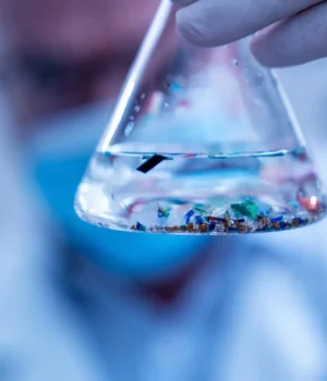 scientist-examining-small-plastic-particles-in-laboratory-flask.webp