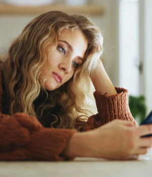 sad-young-adult-female-smartphone-stare.webp